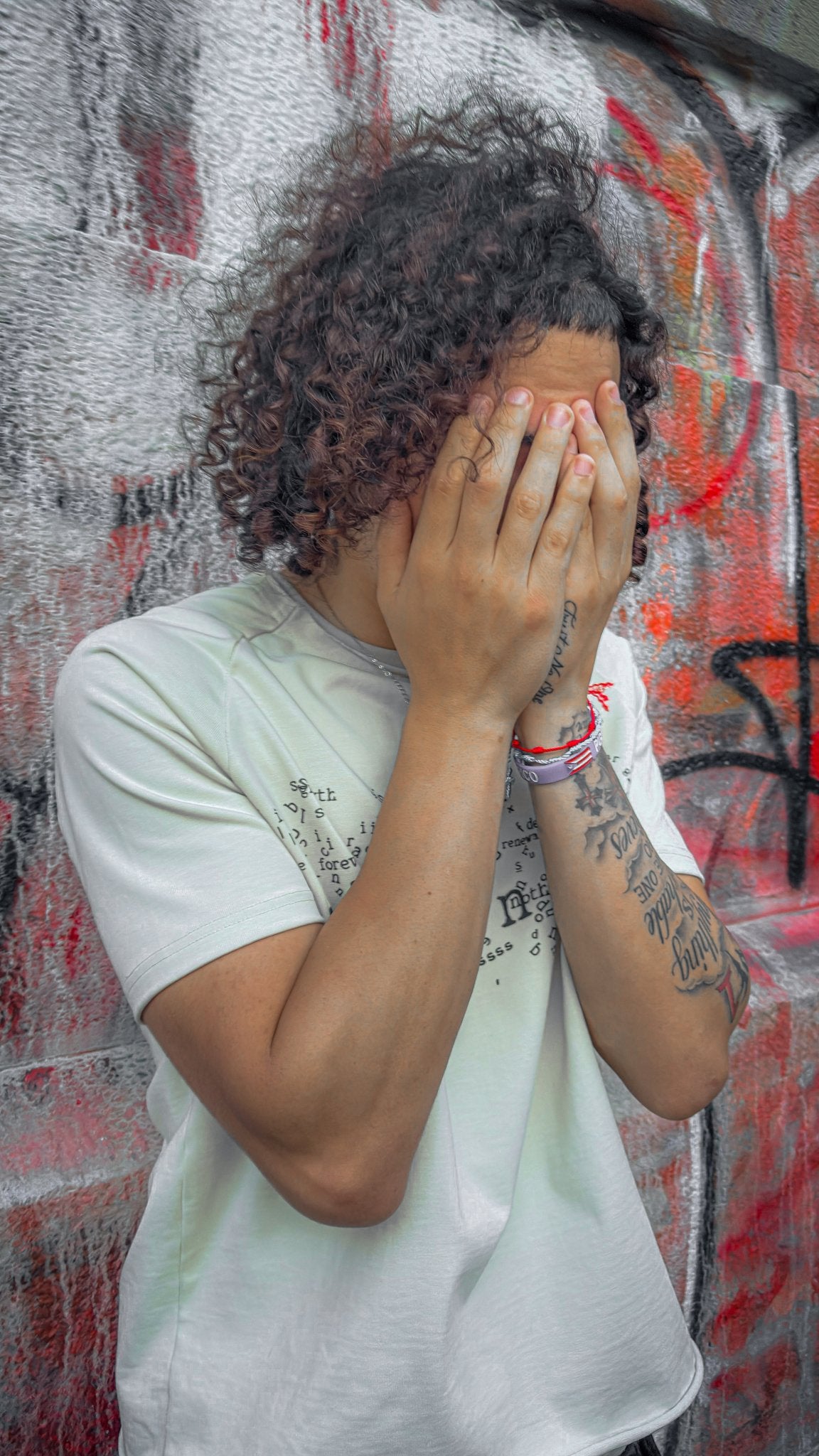 A full-length lifestyle shot of the 6'1" male model wearing the Poem Tee in a slightly angled stance on an urban sidewalk. The composition highlights the oversized boxy geometry of the 325 GSM French Terry tee, detailing the DTG graphics across the torso, the hand-cut Dremel micro-distressing along the collar and hem, the unreleased Y2K 3/4 length shorts, and Balenciaga Runner sneakers.
