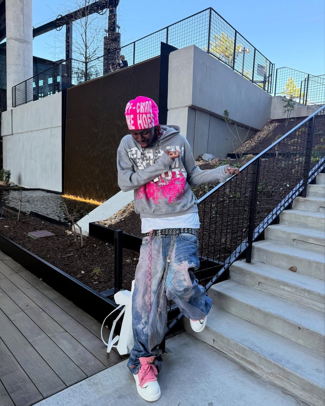 A full-body outdoor lifestyle angle of a model in Atlanta layering the MUST PREVAIL white 425 GSM inside-out tee. The oversized boxy fit is styled with a grey graphic hoodie and baggy denim, showcasing the technical stitching and heavyweight drape of the garment in an urban setting.
