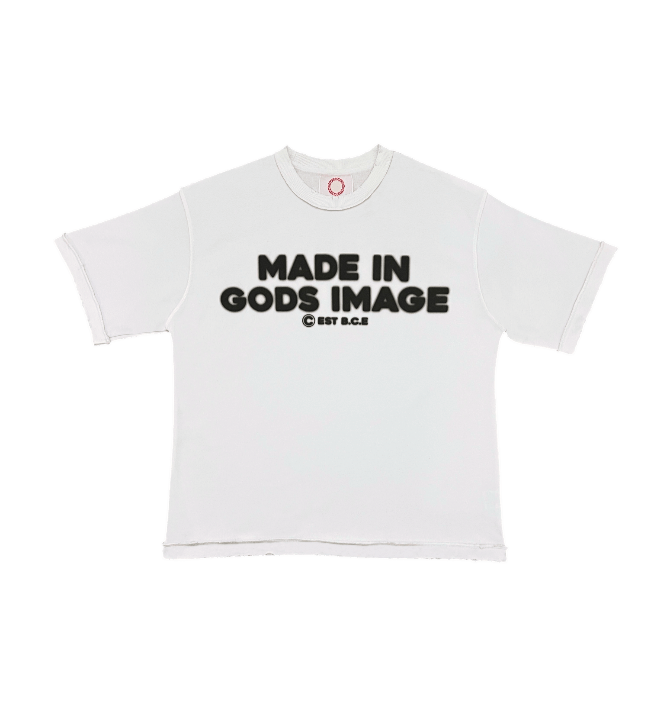 A transparent flat lay of the MUST PREVAIL white 425 GSM heavyweight French Terry inside-out tee. Features 'MADE IN GODS IMAGE' text printed on the front, an oversized boxy fit, inside-out stitching details, and distressed hems for a structural streetwear aesthetic.